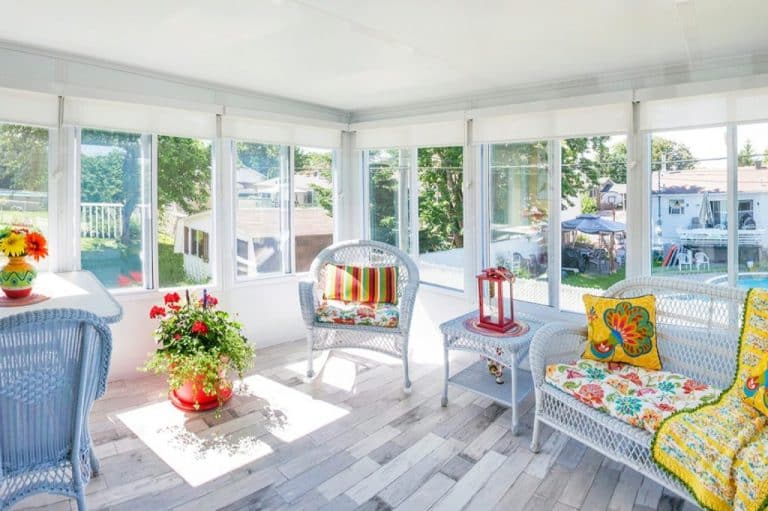 White sunroom looking with furniture looking out a backyard